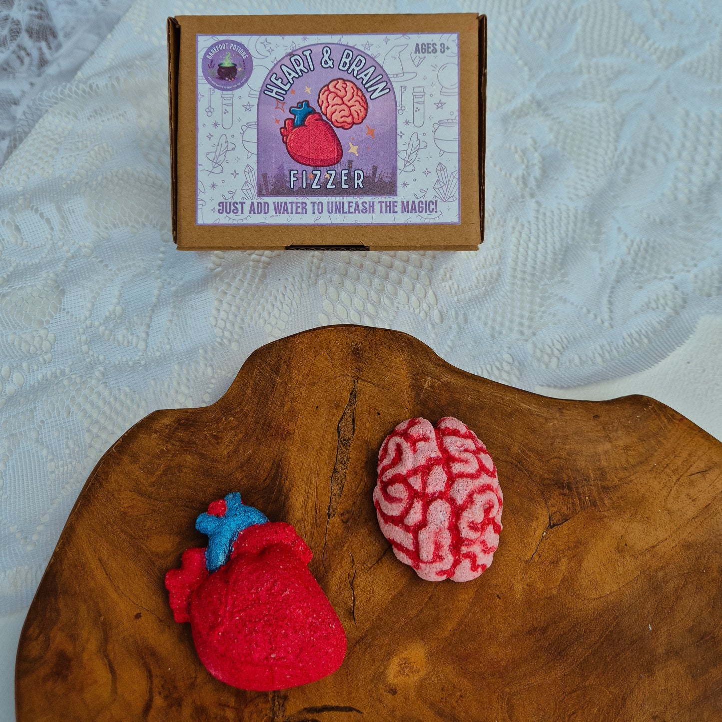 Felt heart and brain fizzers on a wooden surface with a framed picture in the background.