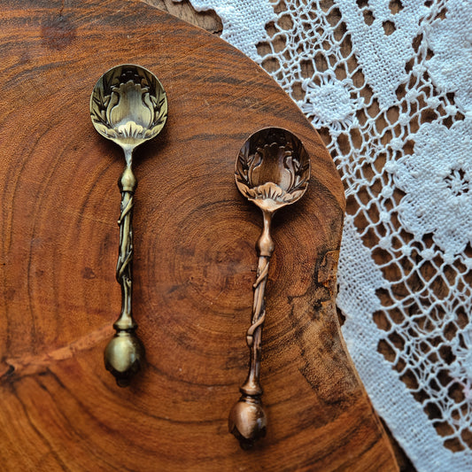 Two decorative spoons with flower bulb shape on a wooden surface with lace in the background. Sensory play for Children