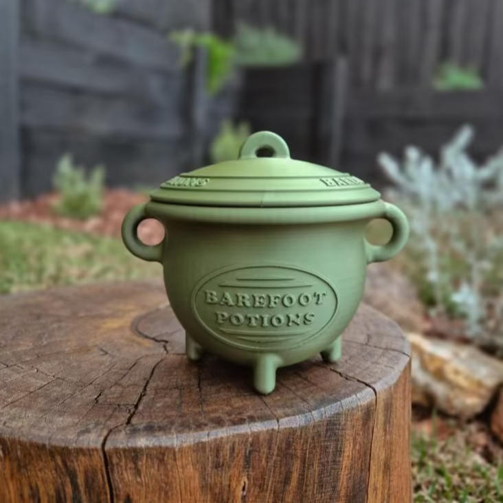 Green Cauldron with a lid on a wooden stump outdoors