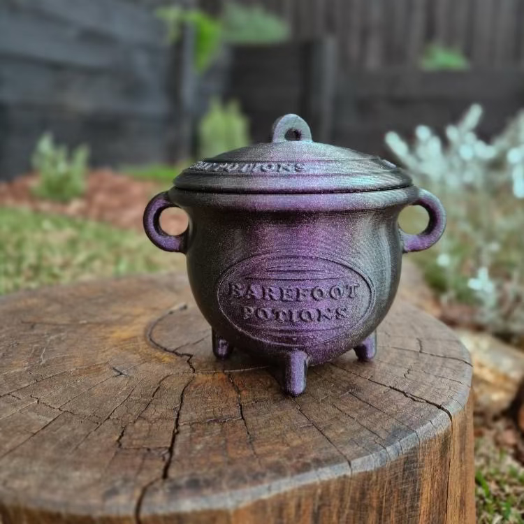 Purple cauldron on a wooden stump with a garden background