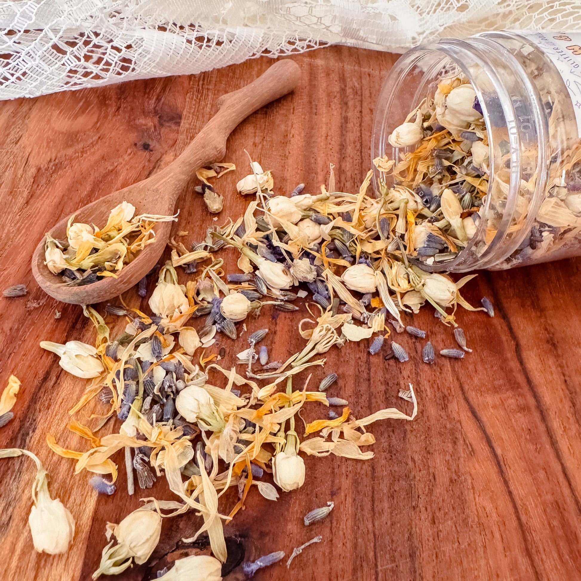 Dried flowers on a wooden surface with a spoon and container. Used for nature and water play with children, sensory exploration.