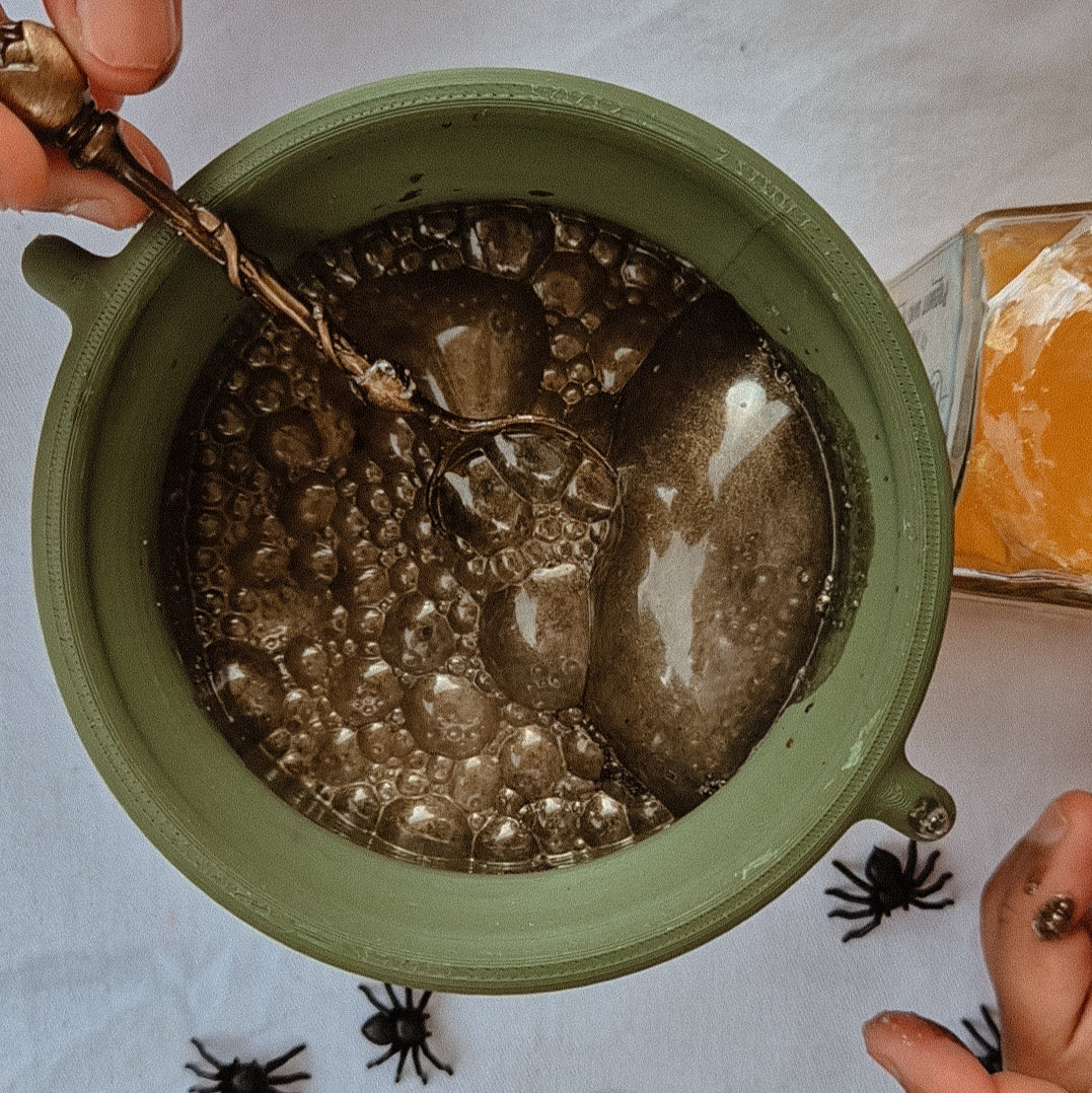 Green play cauldron with bubbling liquid on a Halloween-themed tablecloth