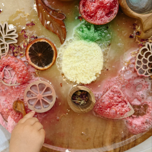 Wooden sensory table with colorful play fizz, dried flowers and wooden tools, for child development and emotional regulation.