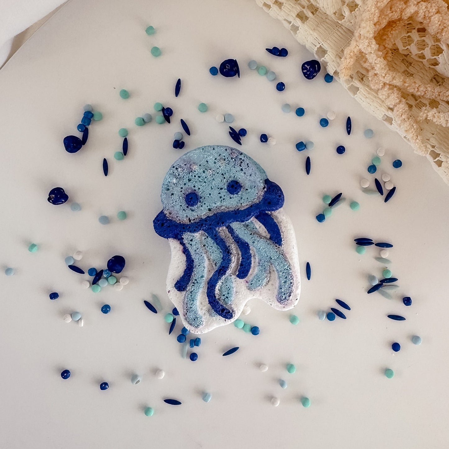Blue jellyfish-shaped object on a white surface with small colorful beads