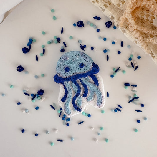 Blue jellyfish-shaped object on a white surface with small colorful beads