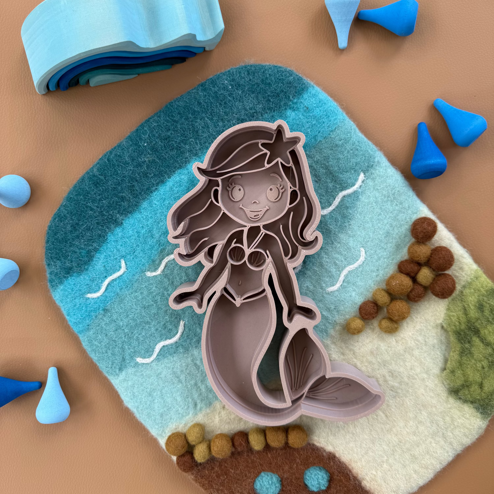 Mermaid sensory tray on a textured surface with decorative ocean elements.