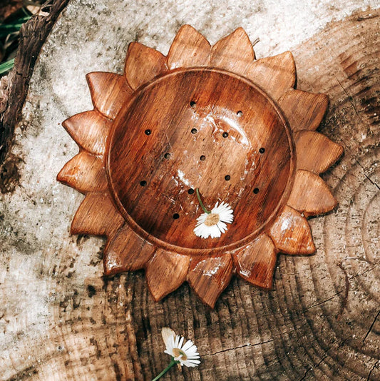 Wooden bowl with sunflower design with strainer, on a wooden surface. For nature play and water exportation with children