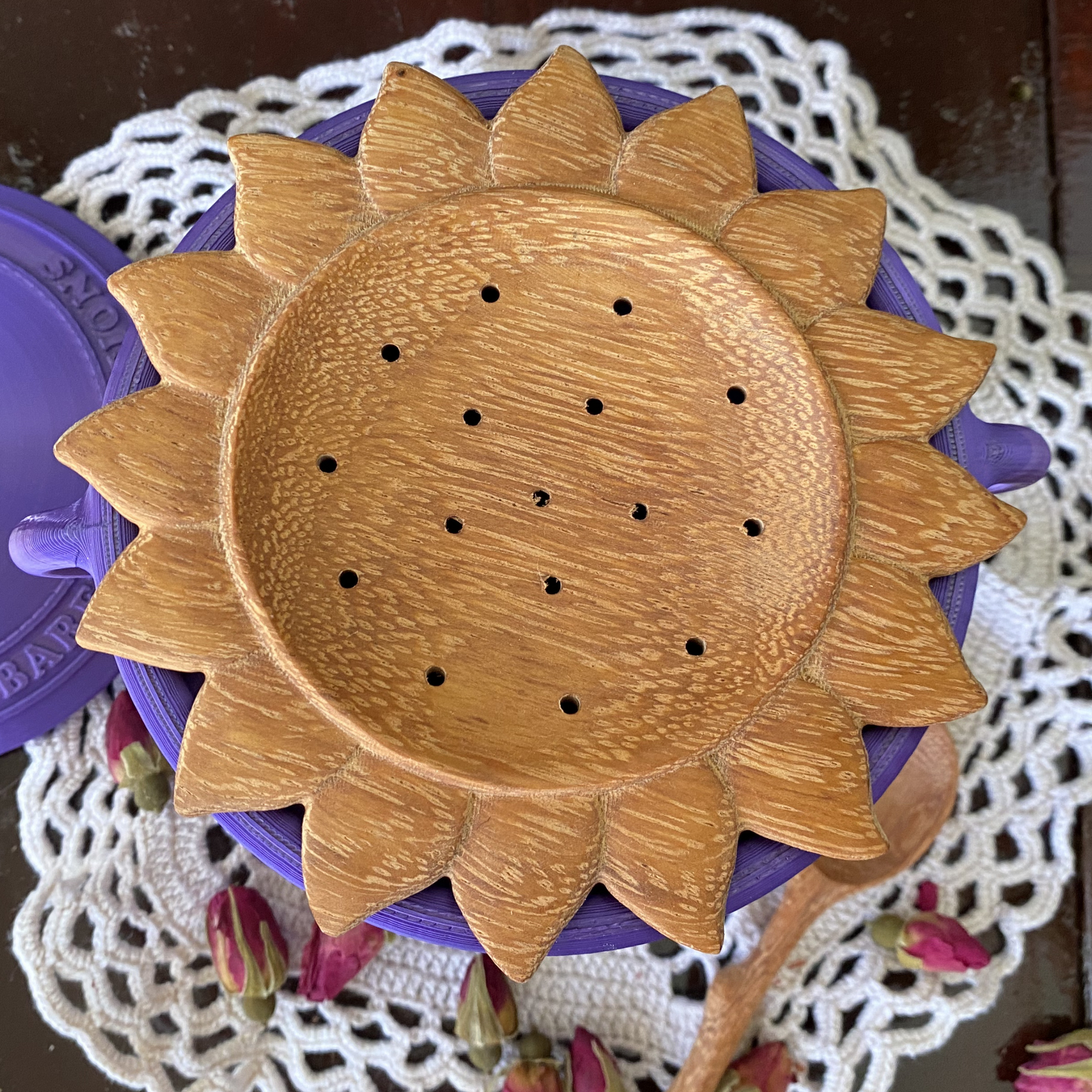 Wooden sunflower-shaped object on a purple barefoot potions cauldron with a white doily underneath