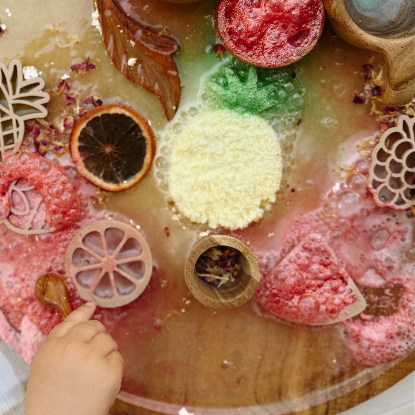 Wooden sensory table with colorful play fizz, dried flowers and wooden tools, for child development and emotional regulation. 