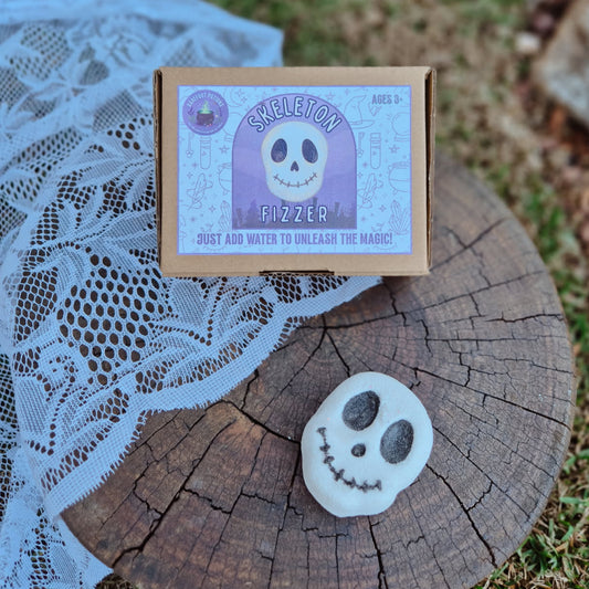 Skelotion Fizzer packaging on a wooden log with a lace cloth and grass background